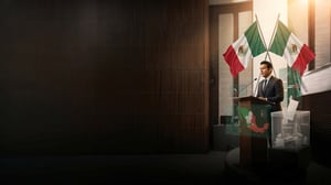Orador en podio con banderas de México y urna electoral, acompañado de gráficos y mapa en pantalla.