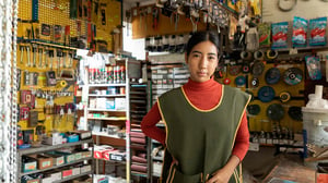 Persona en ferretería organizada con herramientas en pared; atención al cliente y gestión de productos en negocio local.