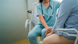 Profesional de salud toma la mano de paciente en consulta; atención cercana, acompañamiento y cuidado médico.